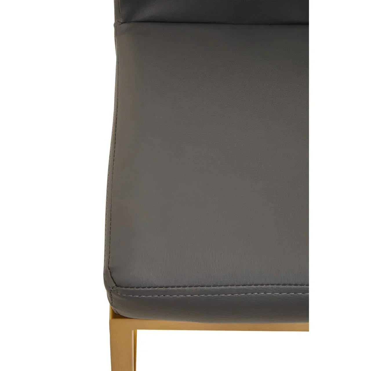 Close-up of grey leather dining chair seat with gold metal leg