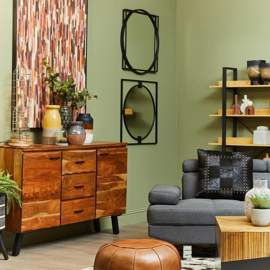 Modern living room with wooden sideboard, grey sofa, leather pouffe, and wall art