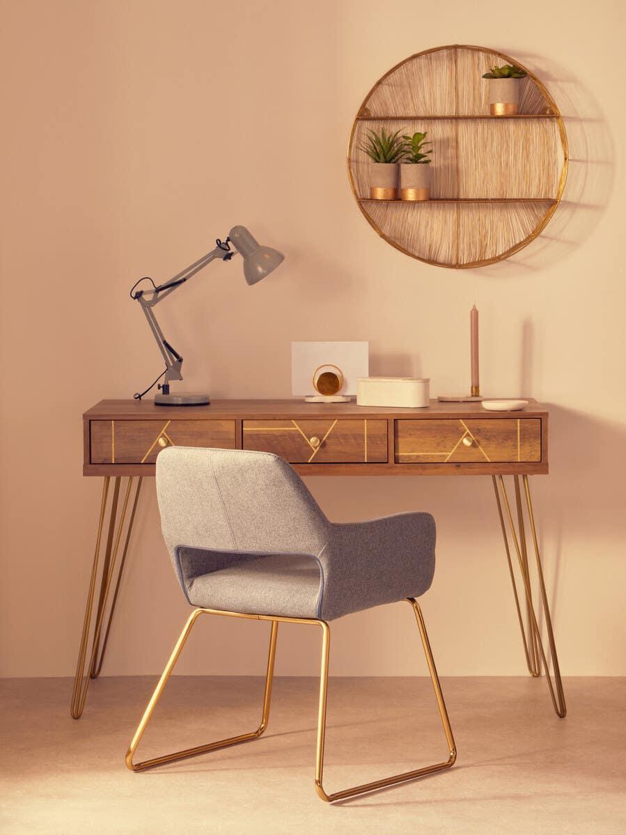 Mid-century wooden desk with gold legs, grey chair, desk lamp, and round wall shelf