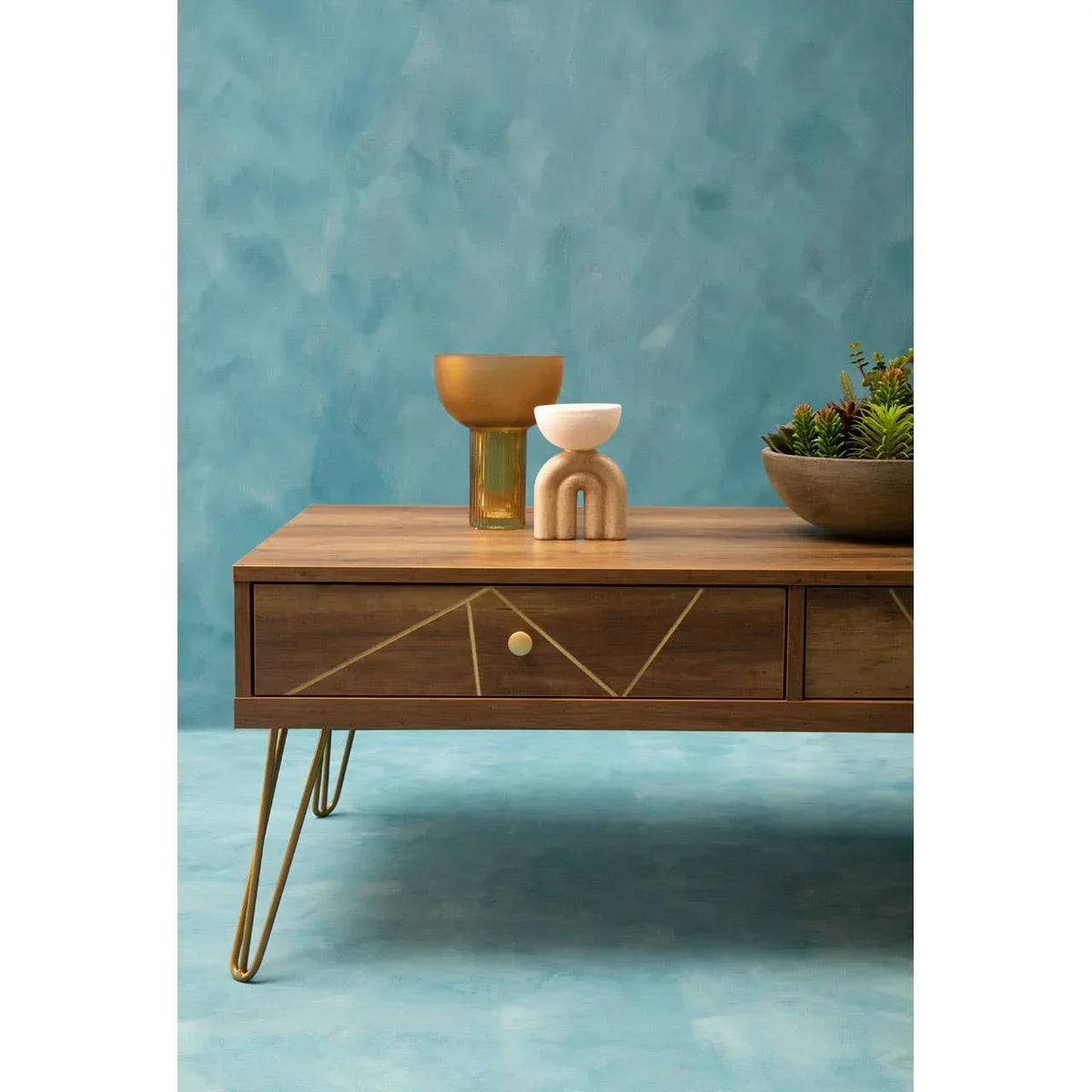 Modern wood coffee table with gold accents and decor against blue wall