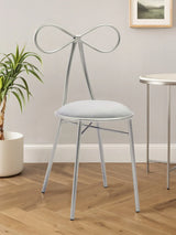 Silver metal dining chair with bow-shaped back and cushioned seat on wooden floor