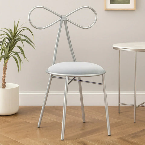 Silver metal accent chair with bow-shaped backrest and cushioned seat in modern room setting