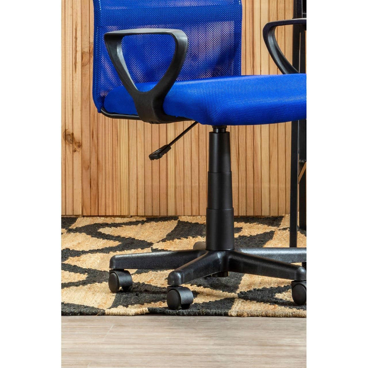Blue mesh office chair with armrests on wheels, side view on patterned rug