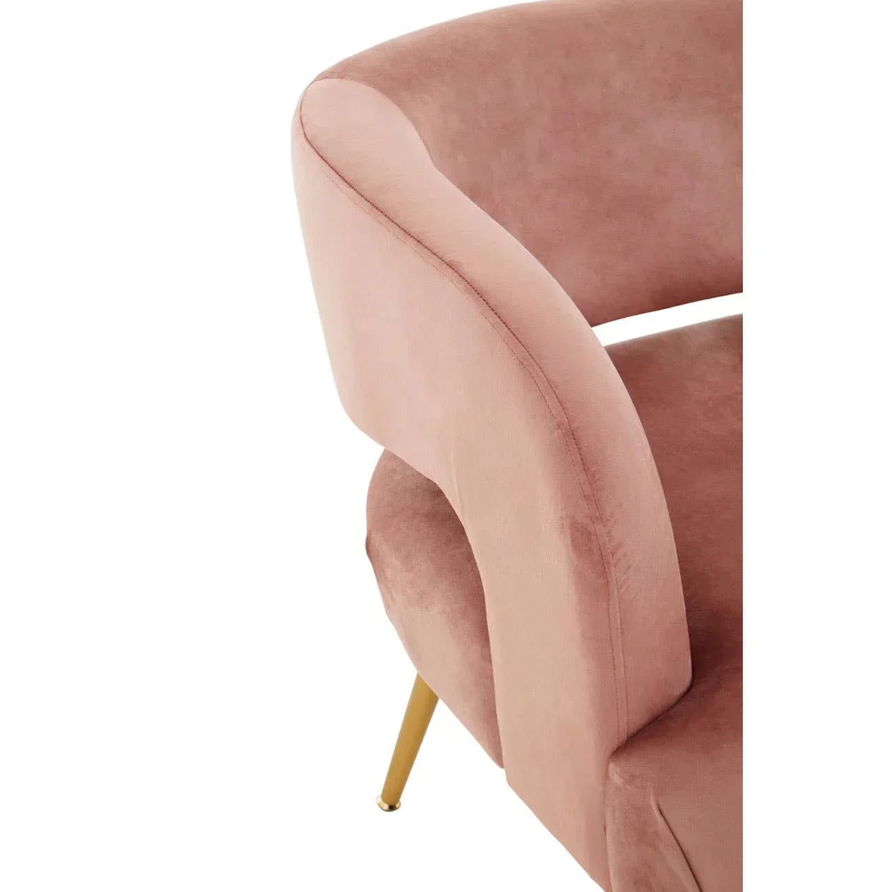 Blush pink velvet accent chair with curved backrest and gold metal legs, close-up side view