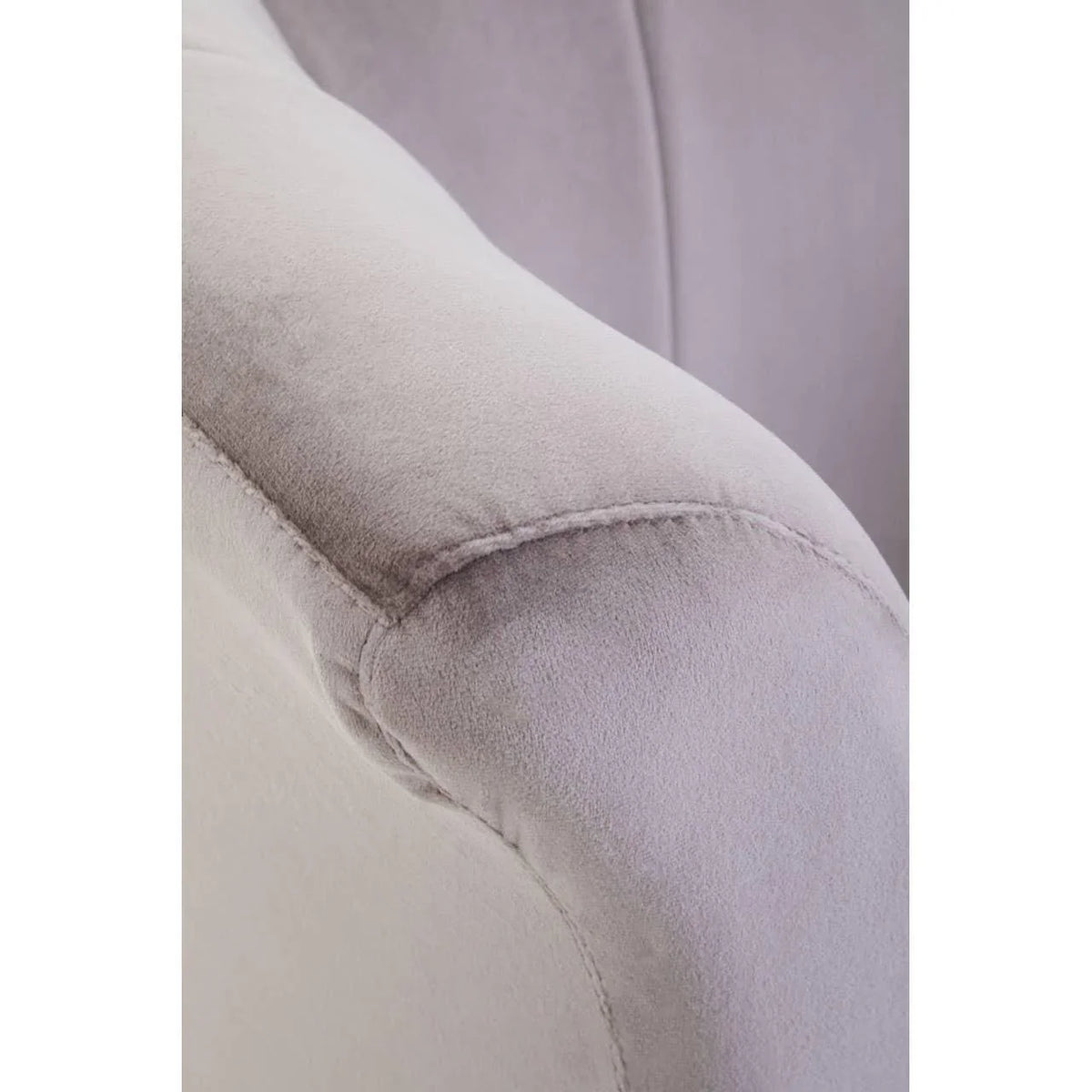 Close-up of light grey velvet sofa armrest with visible stitching detail