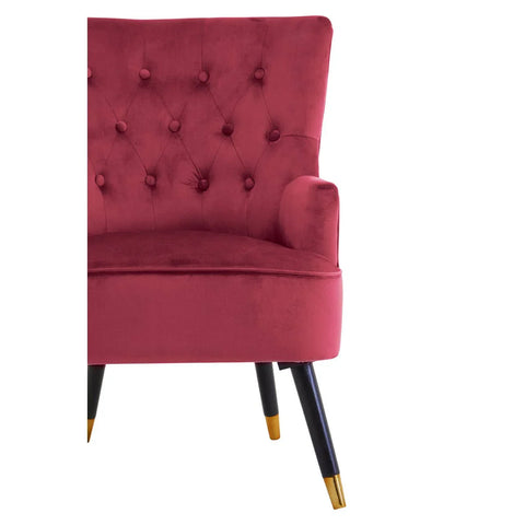 Red velvet accent chair with button-tufted back and black legs with gold tips, side view