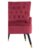 Red velvet accent chair with button-tufted back and black legs with gold tips, side view