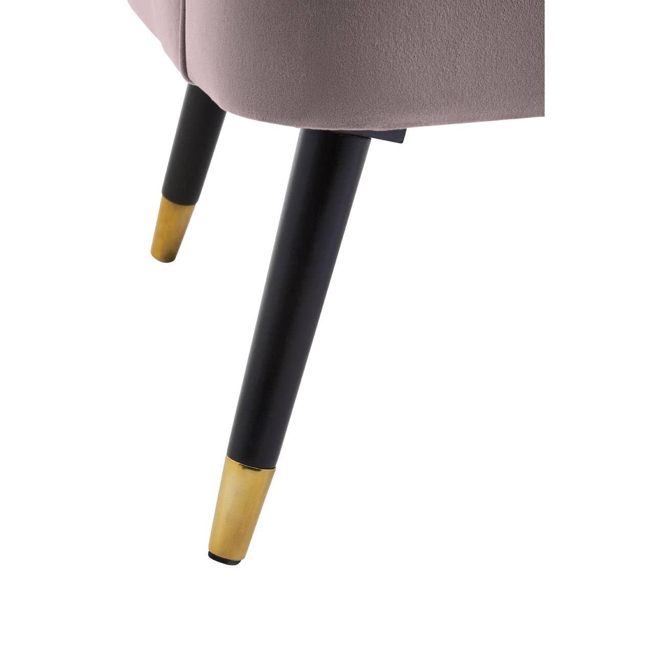 Upholstered chair with black metal legs and gold tips, close up on angled front and back legs