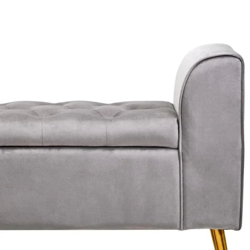 Grey velvet storage bench with gold metal legs and button tufted seat, side view