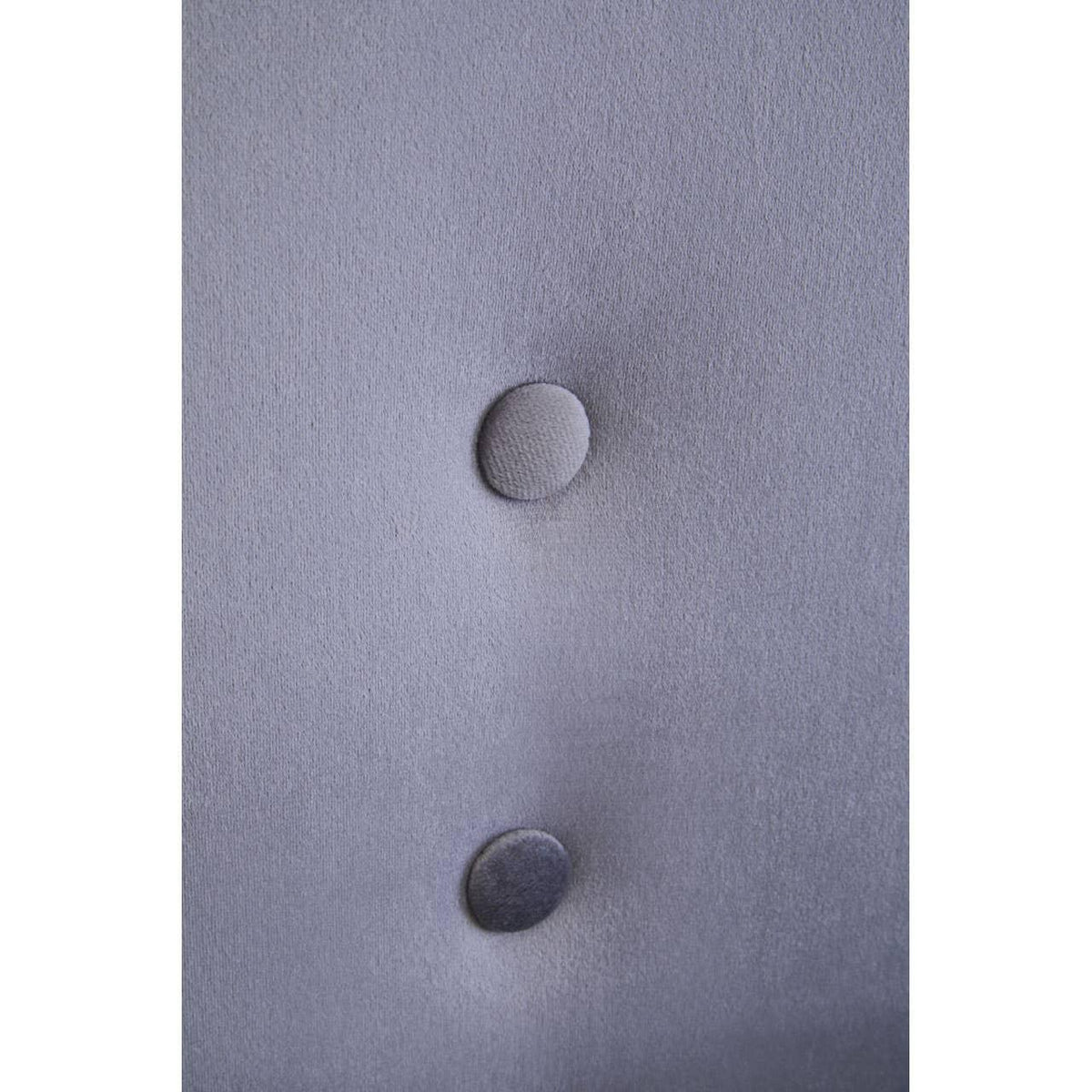 Close-up of grey upholstered headboard with fabric button tufting