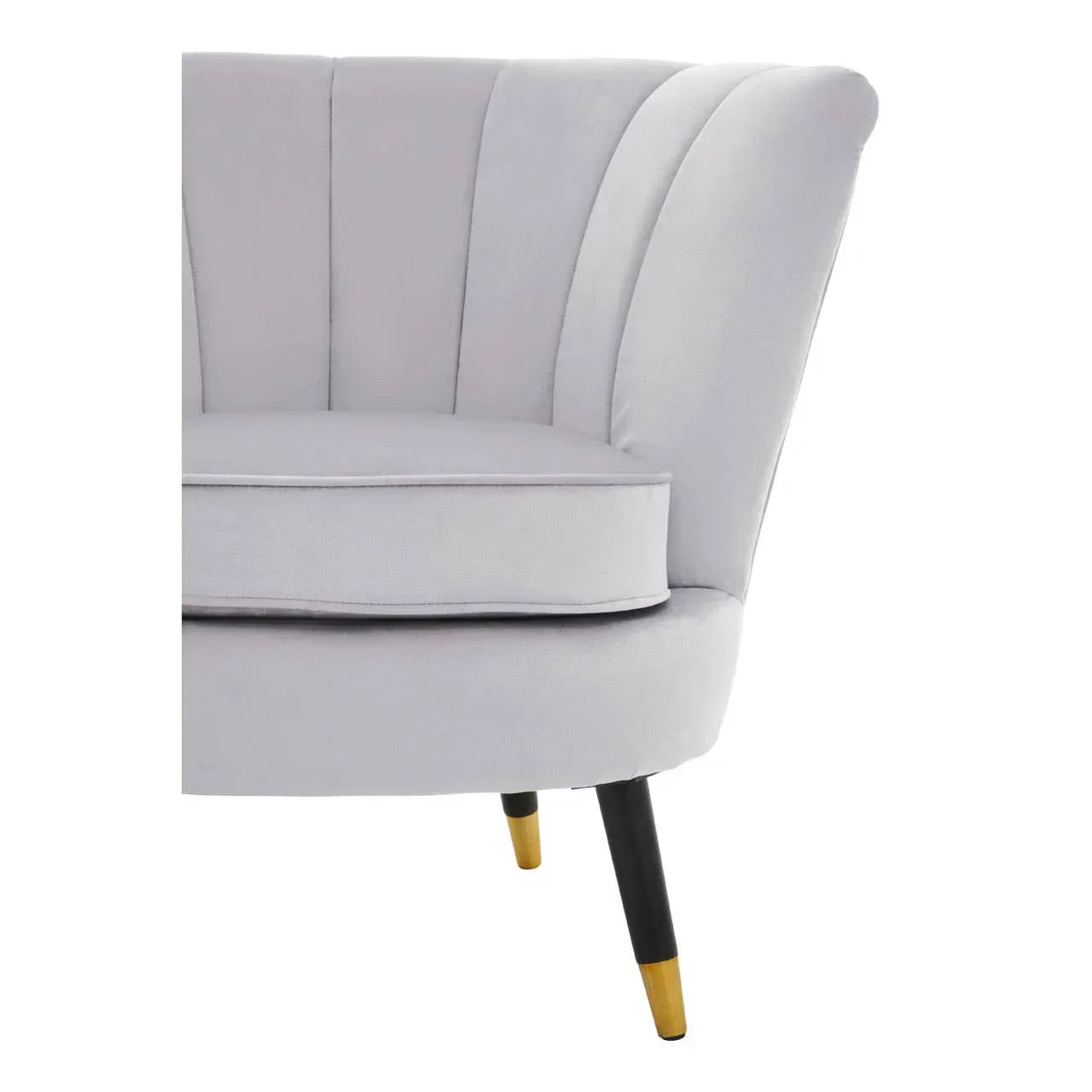 Light grey fabric armchair with scalloped backrest and black legs with gold tips
