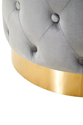 Grey velvet stool featuring a tufted design and a matte gold finish metal base. The base has a smooth, reflective surface that contrasts with the soft texture of the velvet upholstery