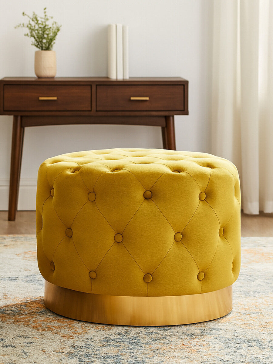 Pistachio velvet stool with a tufted design and a matte gold finish base, placed on a patterned rug in a well-lit room with a wooden console table in the background