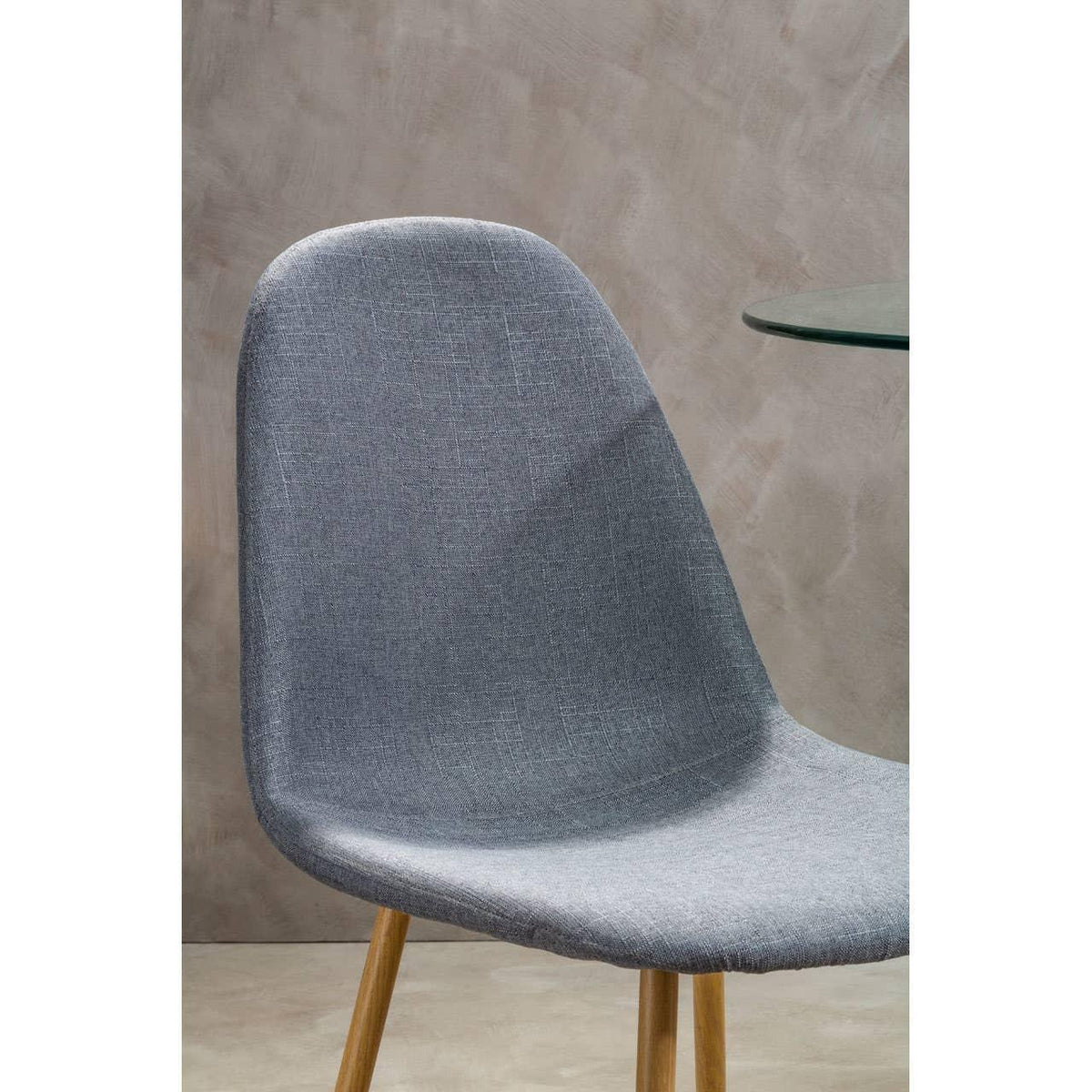 Grey fabric dining chair with wooden legs beside a glass table