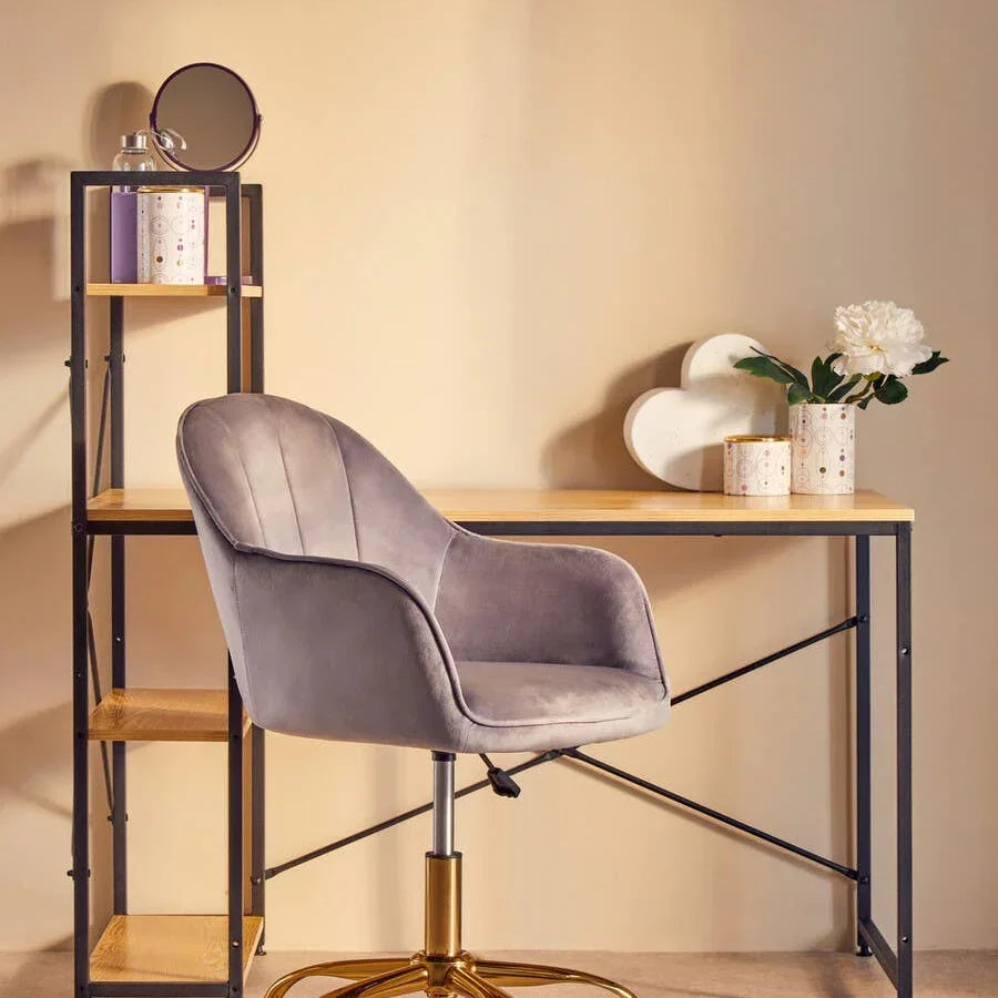 Grey velvet office chair with gold legs at wooden desk and shelving unit with decor items