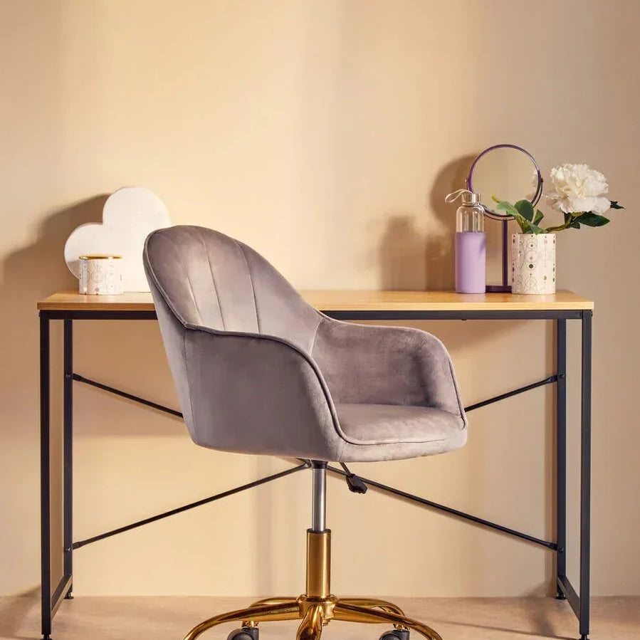 Grey velvet office chair with gold base at modern writing desk, decor and flower vase on top