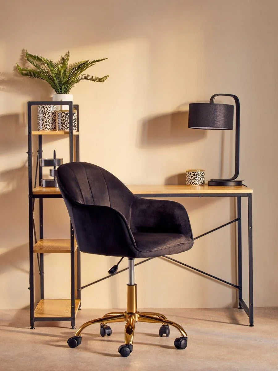 Black swivel office chair with gold base at wood and metal desk, modern home workspace