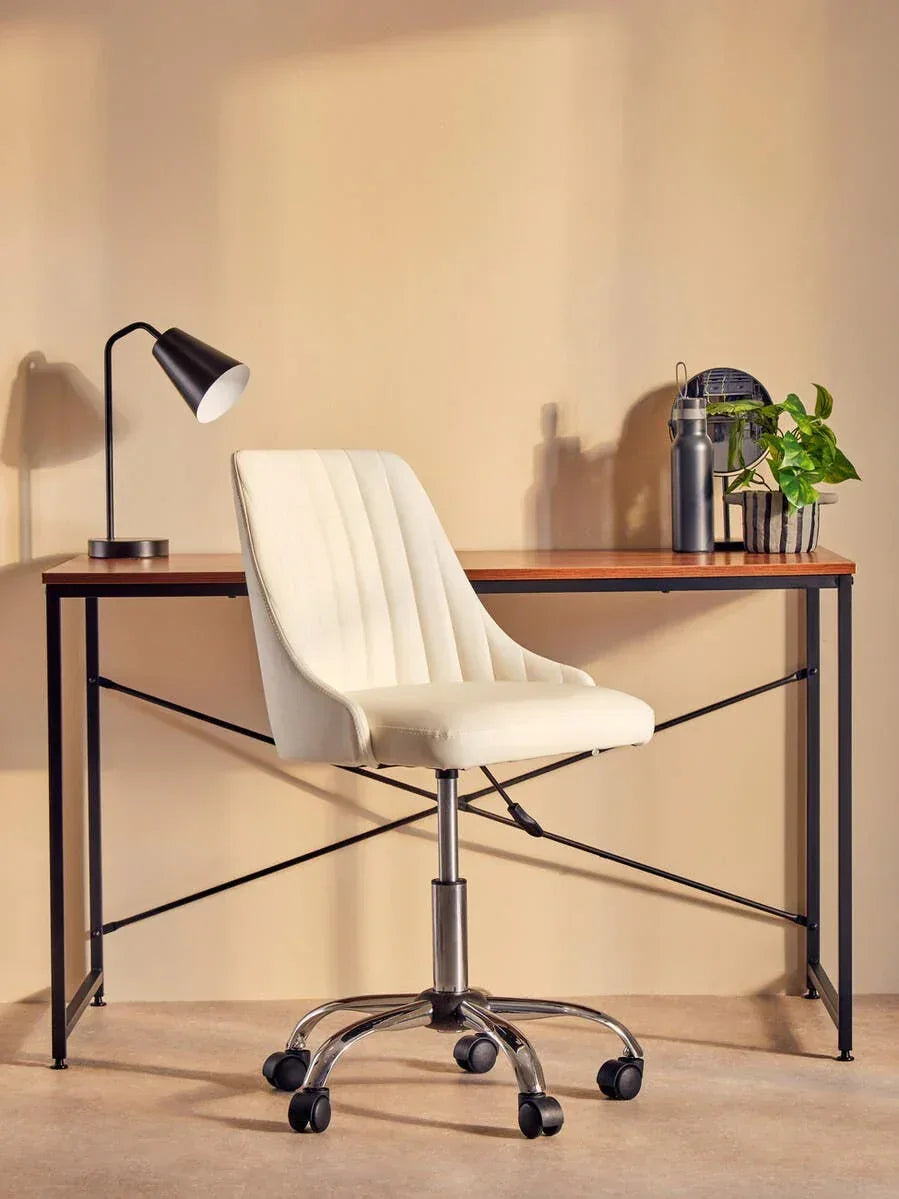 Cream office chair with chrome base at wooden desk, lamp and plant beside for home workspace