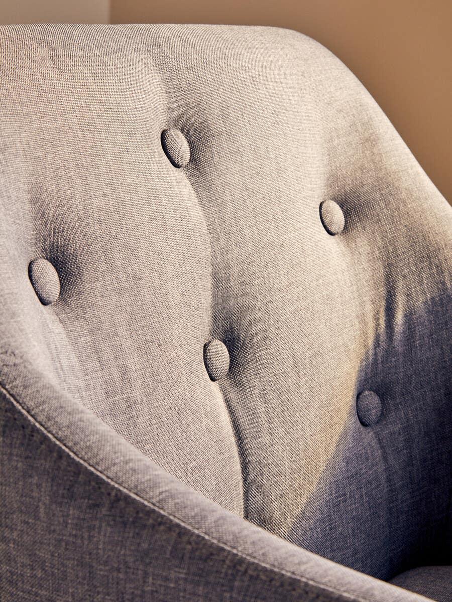 Close-up of grey fabric armchair with button-tufted backrest