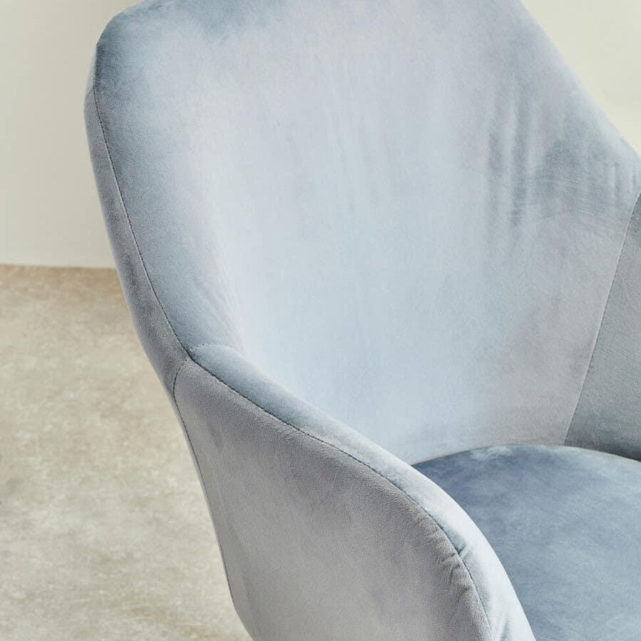 Light grey velvet dining chair with curved backrest and black metal legs