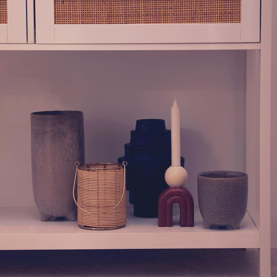 White console table with rattan drawer panel and assorted decorative vases and candle holder