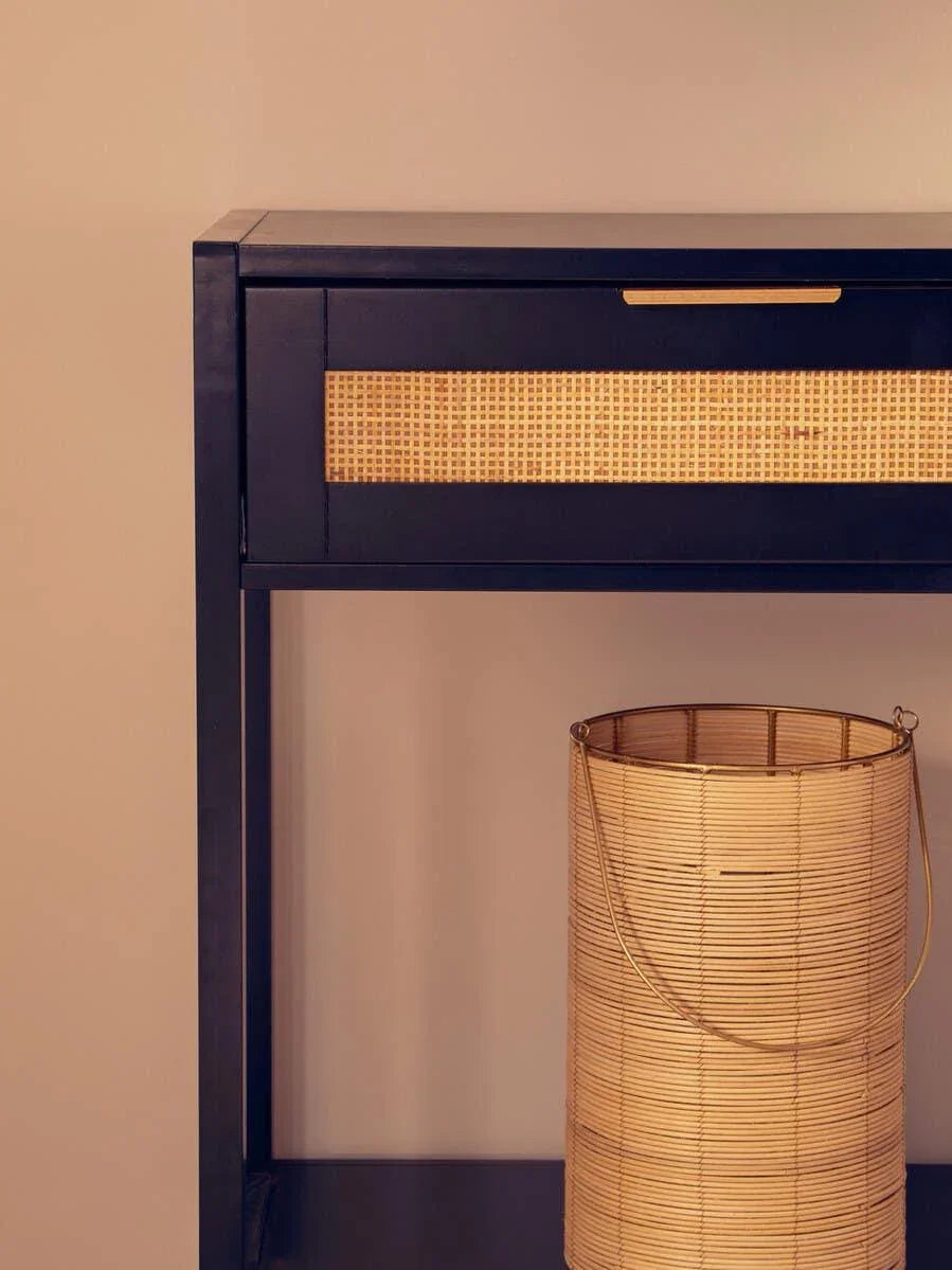 Black console table with rattan drawer and woven bamboo basket placed underneath