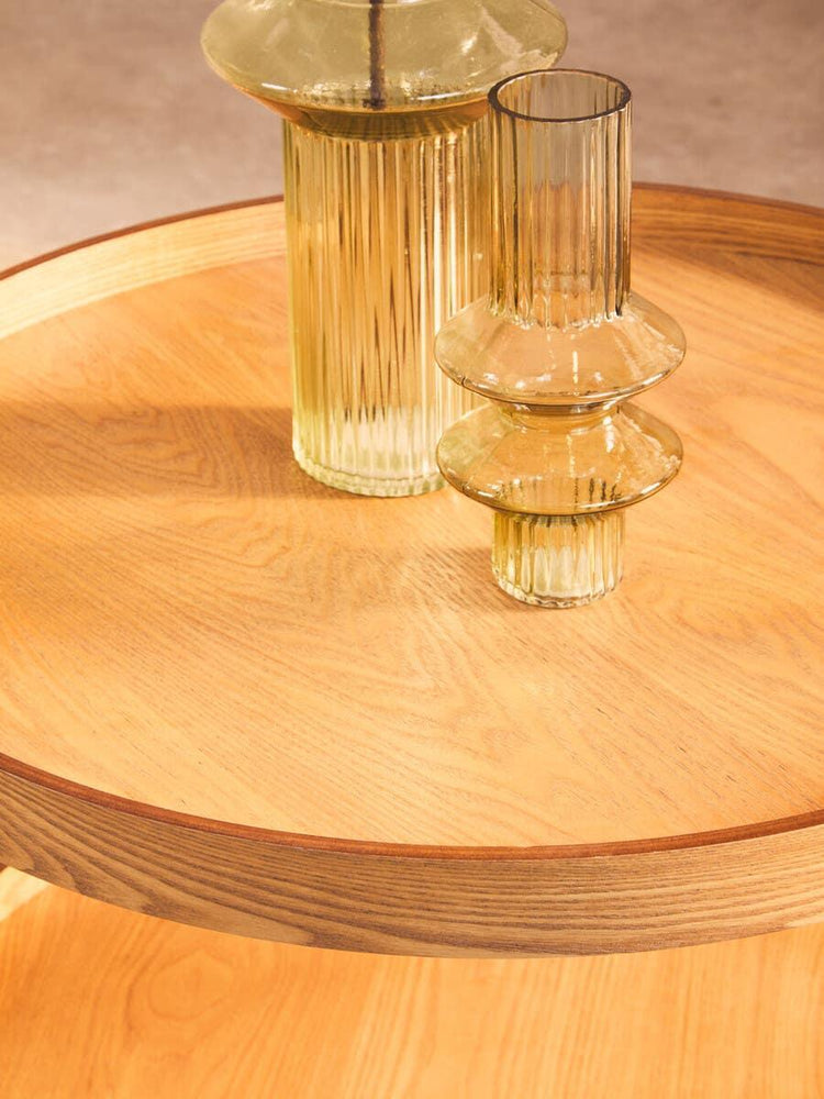 Round wooden table with fluted glass vases as tabletop decor