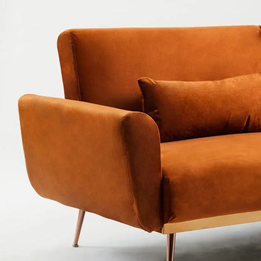 Burnt orange velvet sofa with matching cushion and gold metal legs, angled view