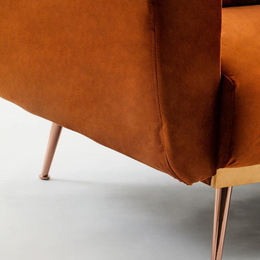 Brown velvet sofa armrest with gold metal legs, corner detail on light background