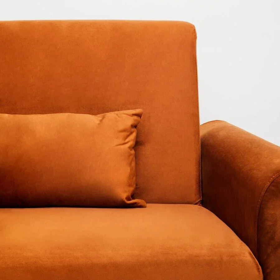 Burnt orange fabric sofa armrest and back with matching cushion, close-up view