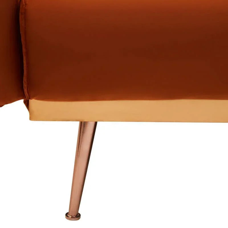 Closeup of orange sofa with gold trim and angled metallic leg