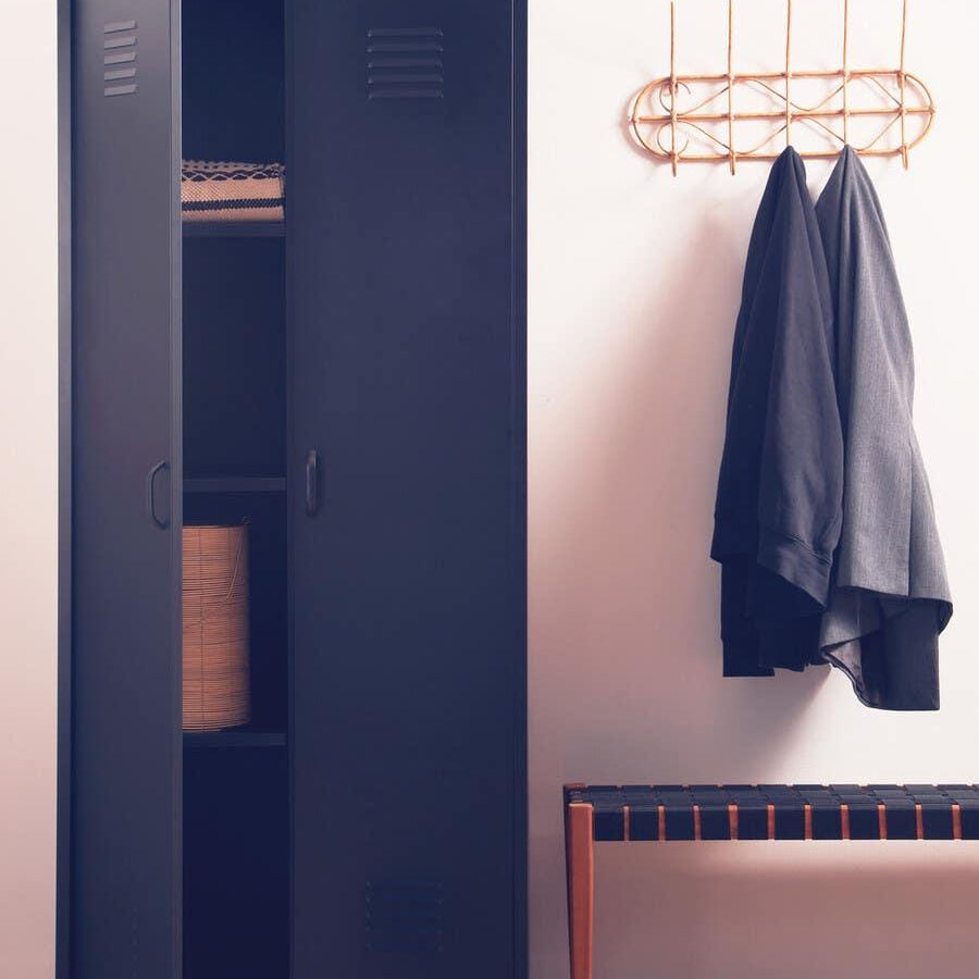Black metal storage cabinet with open doors beside bench and wall coat rack in entryway