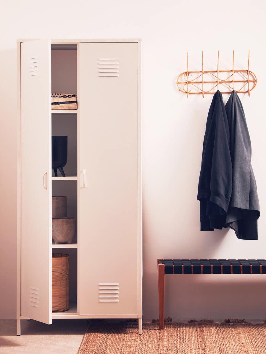 White metal storage cabinet with open doors beside bench and wall coat rack in hallway