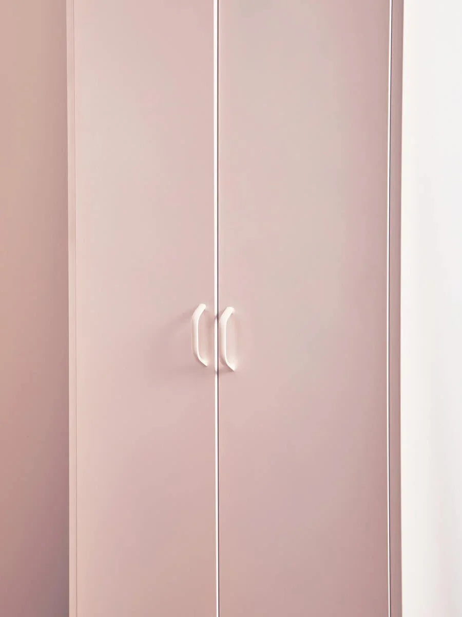 Pink wardrobe with double doors and white handles against a light wall