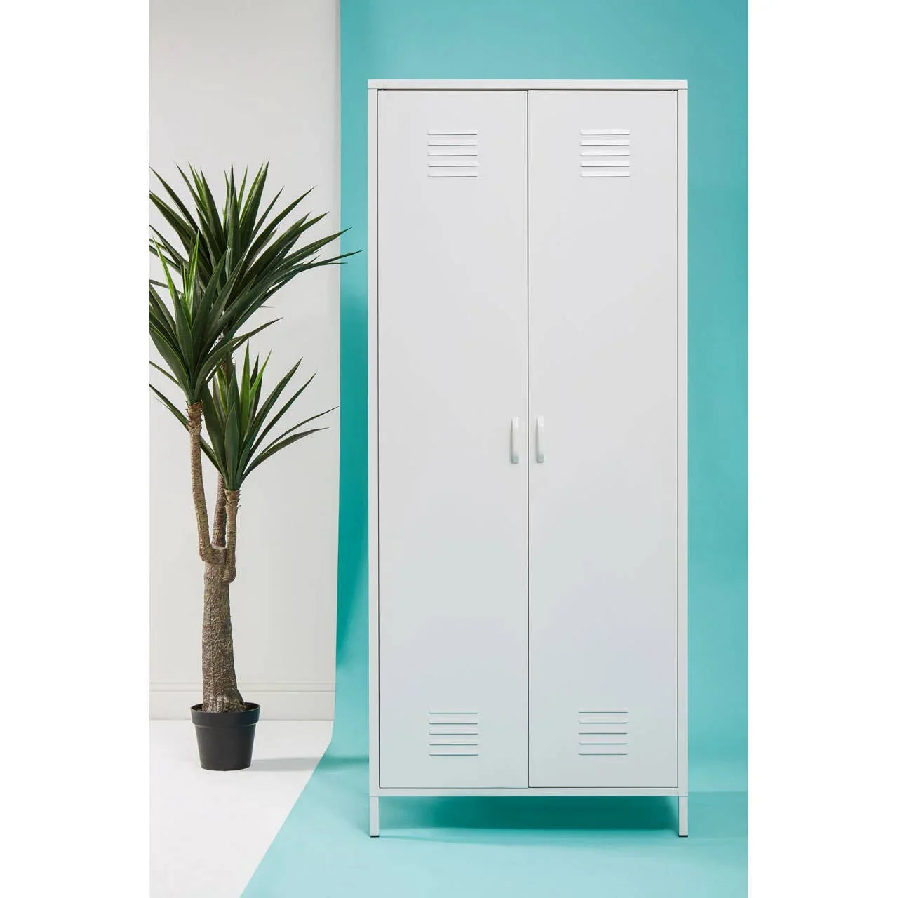 White metal storage cupboard with double doors and handles, set beside a potted plant