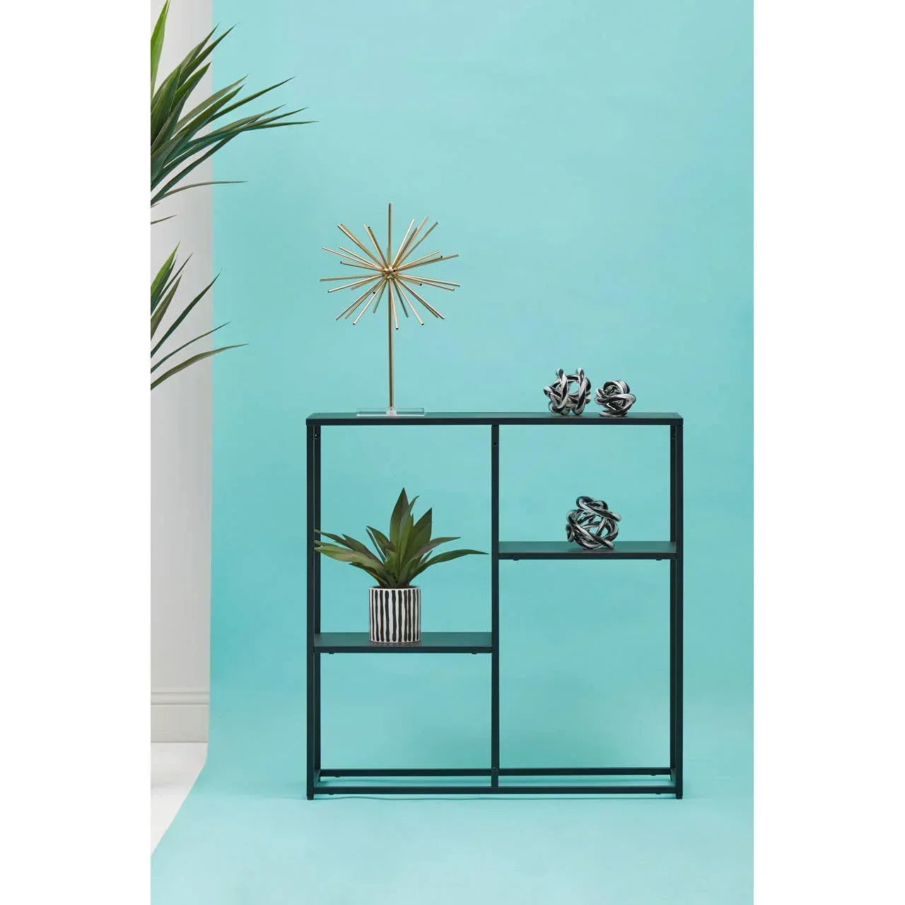 Black metal display shelving unit with geometric decor and potted plant against blue background