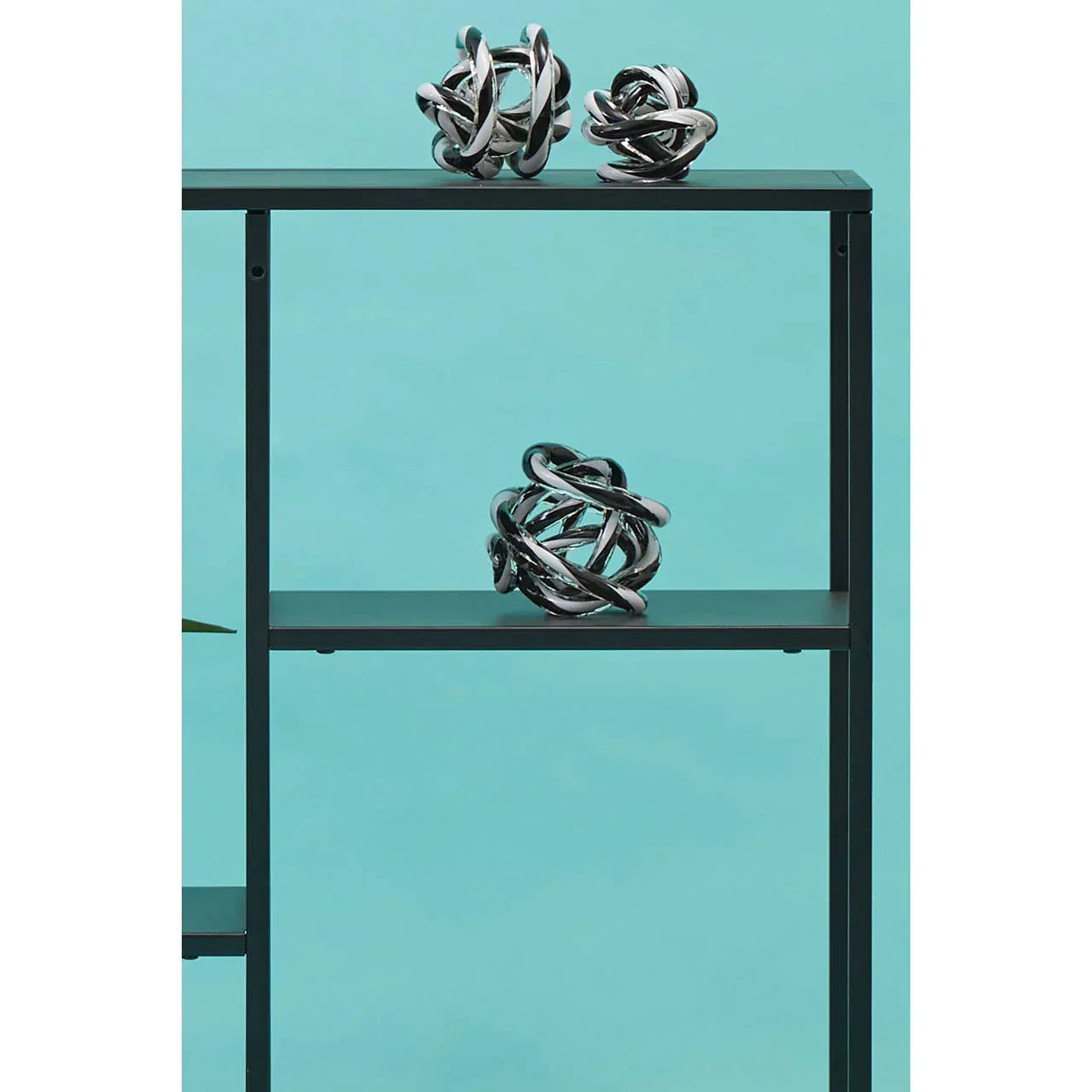 Black metal shelving unit with chrome decorative ornaments against blue wall