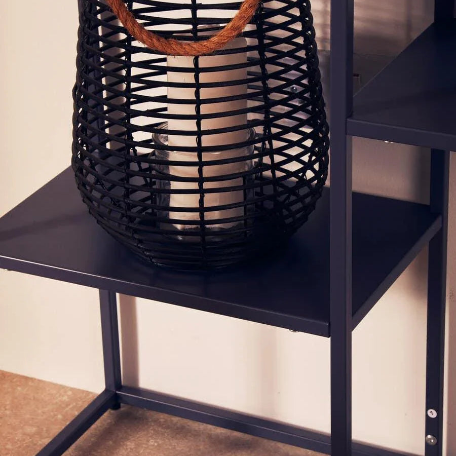 Black metal shelf with rattan lantern and candle, close-up on home decor display