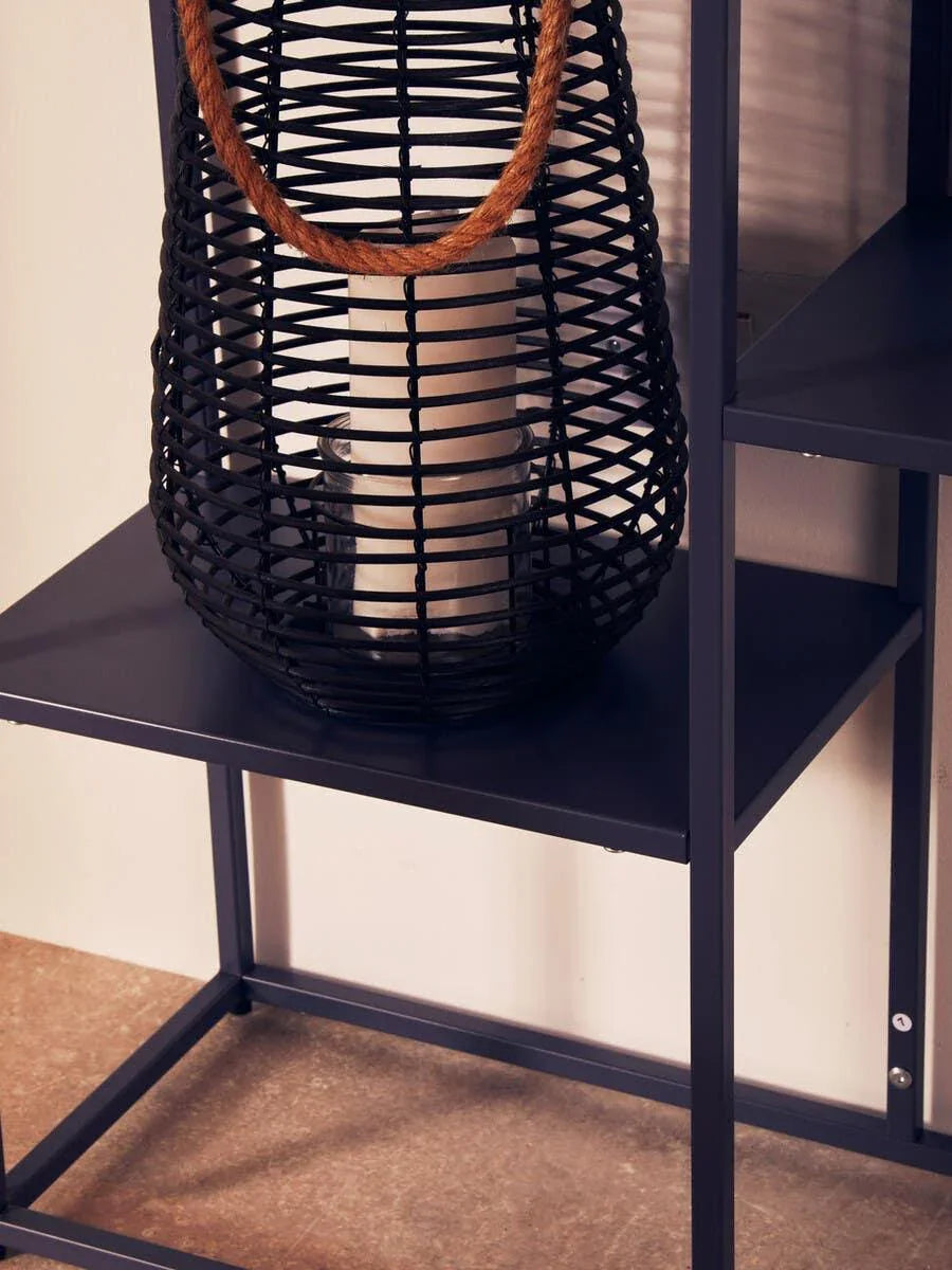 Black metal shelf with rattan lantern and candle, close-up on home decor display
