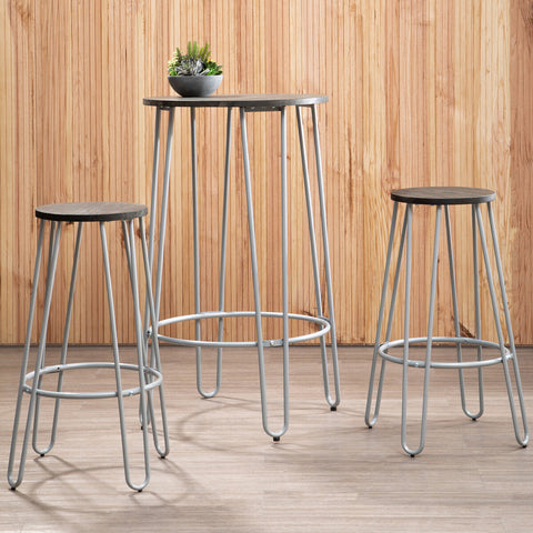 A three-piece bar table and stool set featuring a tall, slender elm wood table with a natural finish and sleek metal legs, accompanied by two matching stools with round seats and metal frames. A small potted plant sits on the table, and the background consists of wooden paneling, creating a warm and inviting atmosphere
