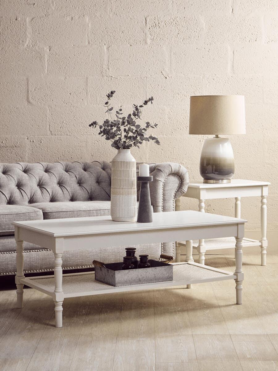 White wooden coffee table and side table with lamp beside grey buttoned sofa in living room