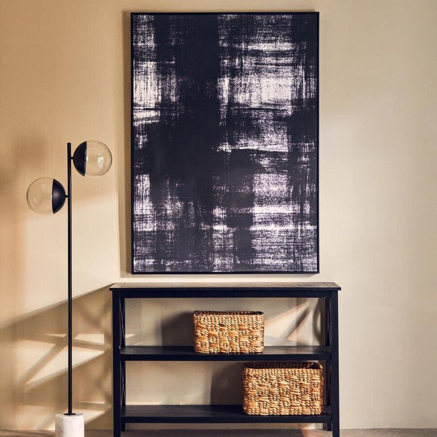 Black console table with woven storage baskets and abstract wall art against beige wall