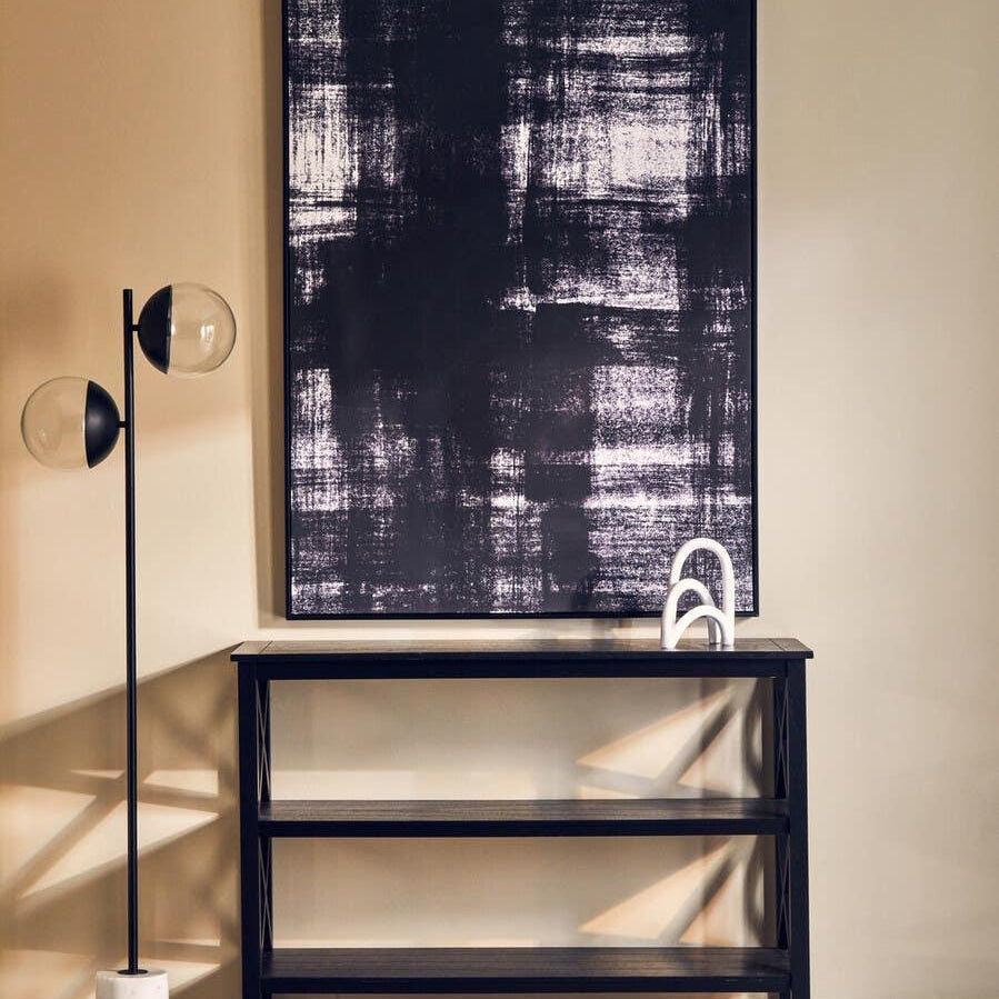 Black console table with marble effect top, modern floor lamp, abstract wall art
