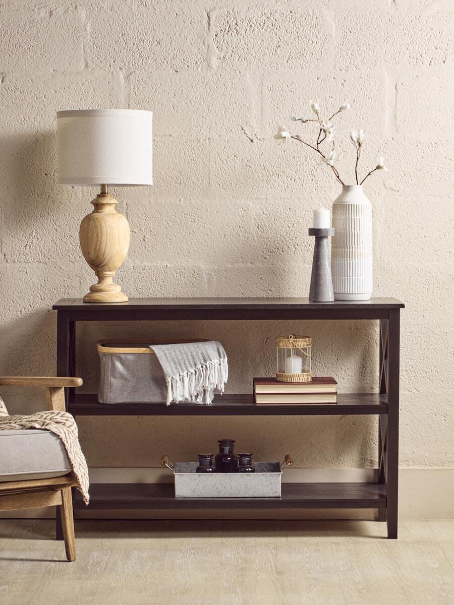 Dark wood console table with lamp, ceramic vase, storage basket and decorative tray
