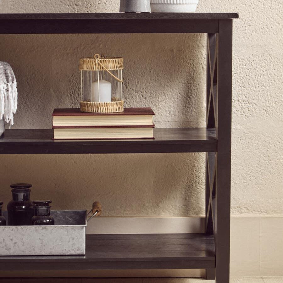 Dark wood console table with decorative vases, books, and a rattan lantern on shelves