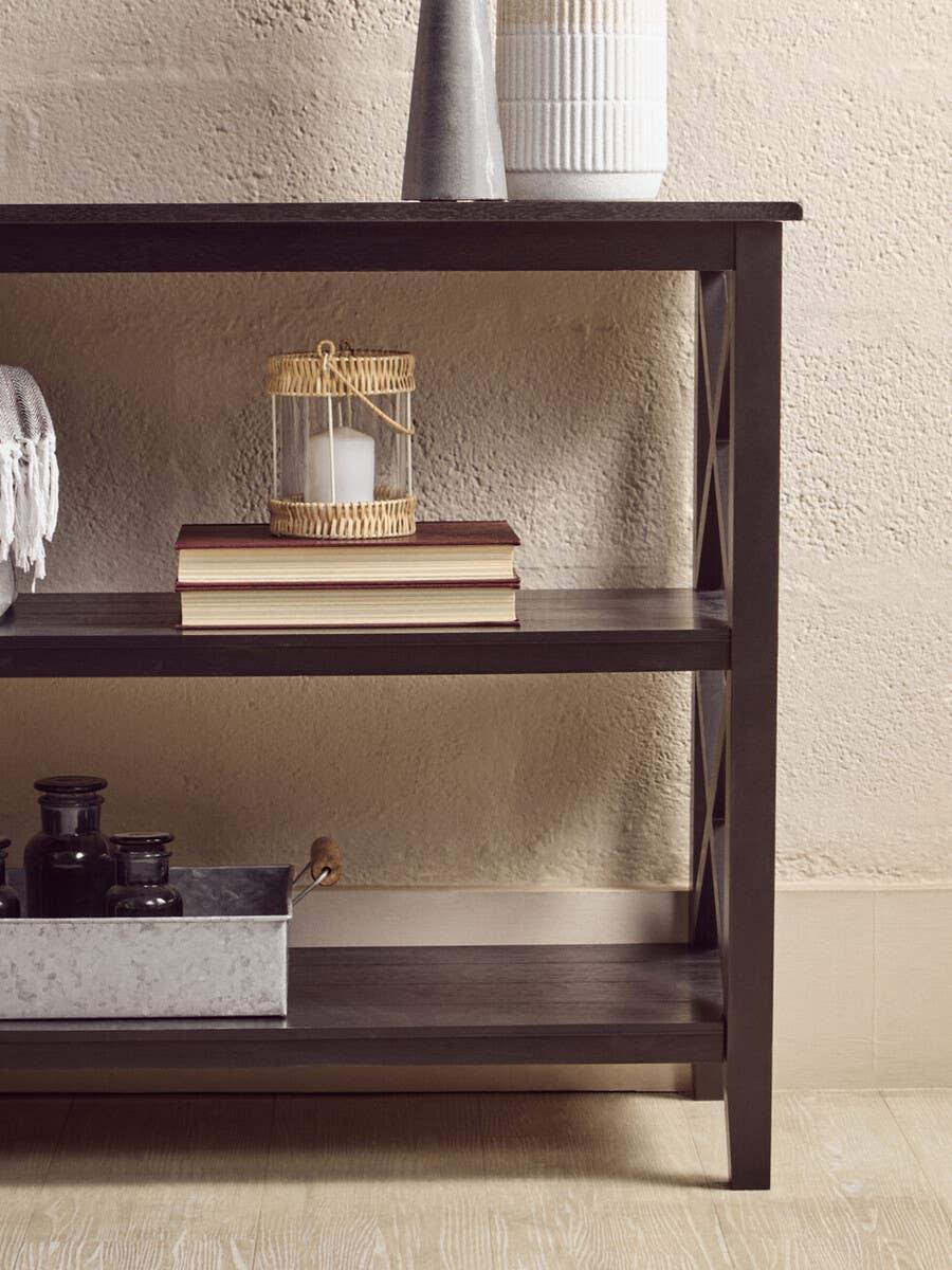 Dark wood console table with decorative vases, books, and a rattan lantern on shelves
