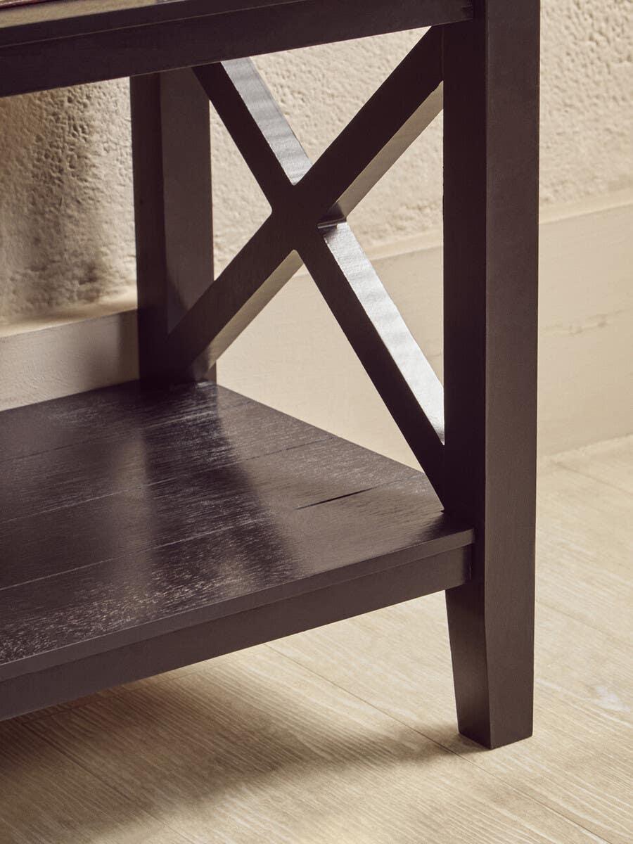 Dark wood furniture leg with X-frame detail and lower shelf on light flooring
