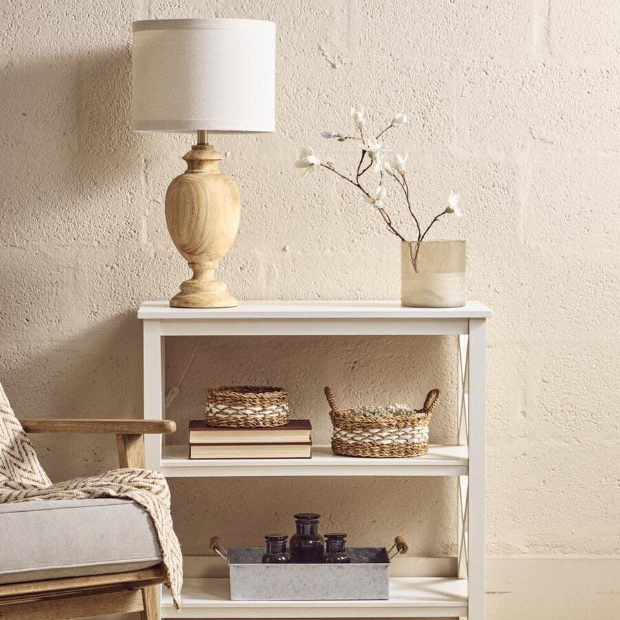 White wooden console table with lamp, books, baskets and vase in living room setting