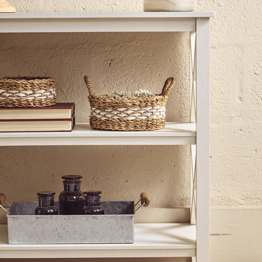 White wooden console table with wicker baskets and vases, styled against a textured wall