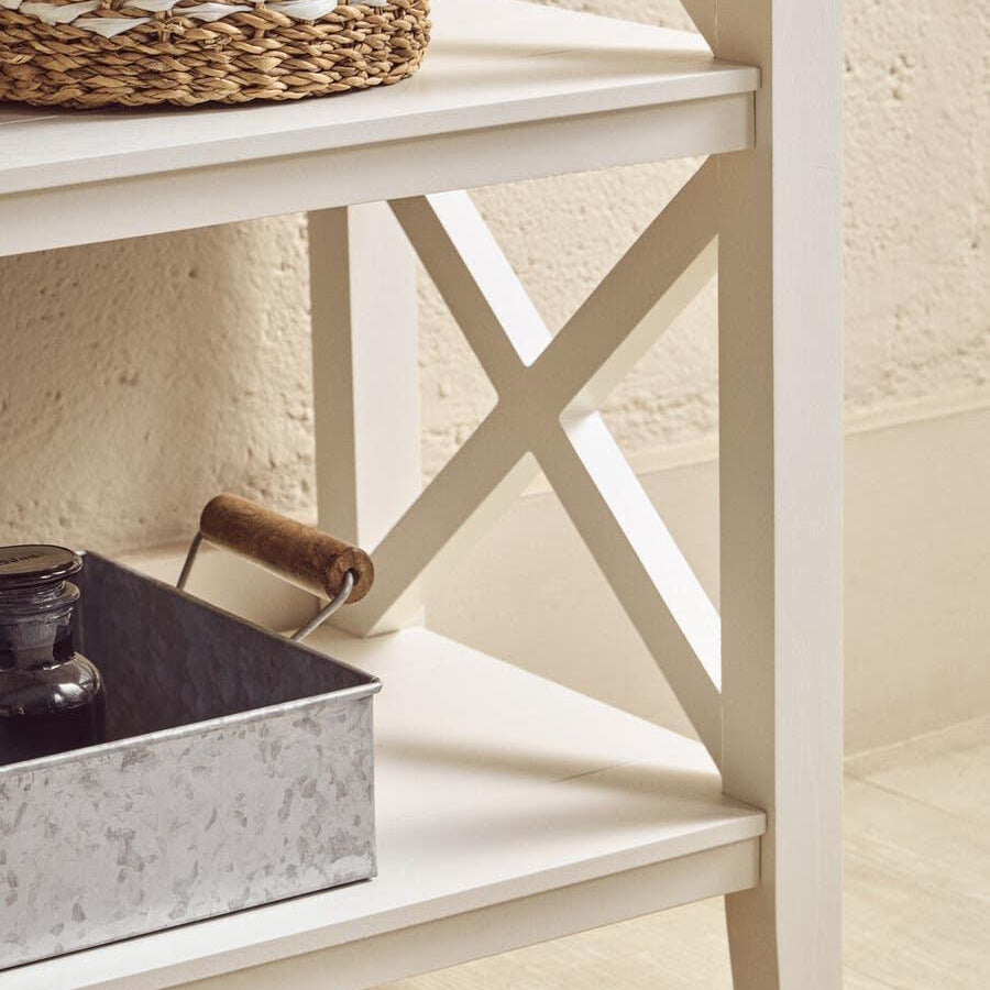 White wooden shelving unit with cross-frame detail and storage basket on lower shelves